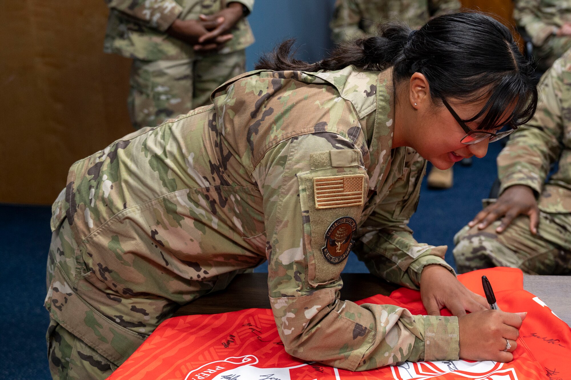 U.S. Air Force Staff Sgt. Christiana Salas, the noncommissioned officer in charge of intelligence operations assigned to the 36th Tactical Advisory Squadron, signs the Linebacker of the Week jersey at Andersen Air Force Base, Guam, Aug. 2, 2023. The Team Andersen Linebacker of the Week recognizes outstanding enlisted, officer, civilian and total force personnel who have had an impact on achieving Team Andersen’s mission, vision and priorities. (U.S. Air Force photo by Airman 1st Class Emily Saxton)