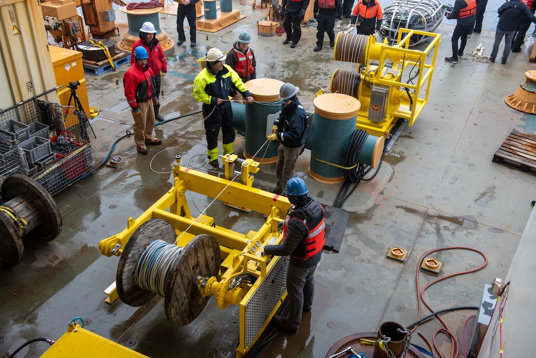 Researchers aboard Coast Guard Cutter Healy (WAGB 20) prepare a winch for the Very Low Frequency Sound Source deployment in the Beaufort Sea, Aug. 2, 2023. Healy is designed to conduct a wide range of research activities, providing more than 4,200 square feet of scientific laboratory space, numerous electronic sensor systems, oceanographic winches, and accommodations for up to 50 scientists. (Coast Guard photo by Petty Officer 3rd Class Briana Carter)