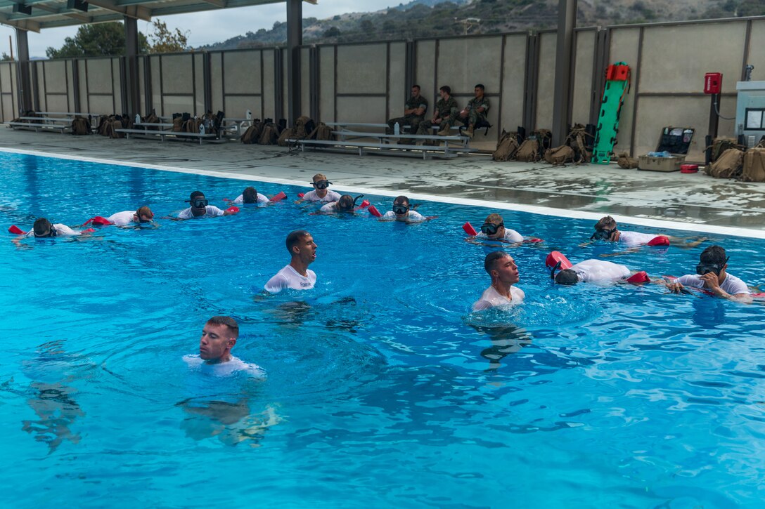 U.S. Marine Corps Basic Reconnaissance Primer Course 9-18 students with Reconnaissance Training Company, Advanced Infantry Training Battalion, School of Infantry-West, supervise classmates who are conducting a bobbing exercise in which students exhale all the air in their lungs, sink to the bottom of the pool, and then return to the surface as a part of the Reconnaissance Aquatics Competency Test (RACT) at the Area 53 Pool at Marine Corps Base Camp Pendleton, California, Sept. 24, 2018. The RACT consisted of each student executing a series of aquatic exercises while having their feet tied together and keeping their hands behind their backs. The students conducted the RACT in preparation for follow-on training in the U.S. Marine Corps Combatant Diver Course where the same test is a requirement for course completion. (U.S. Marine Corps photo by Lance Cpl. Kerstin Roberts)