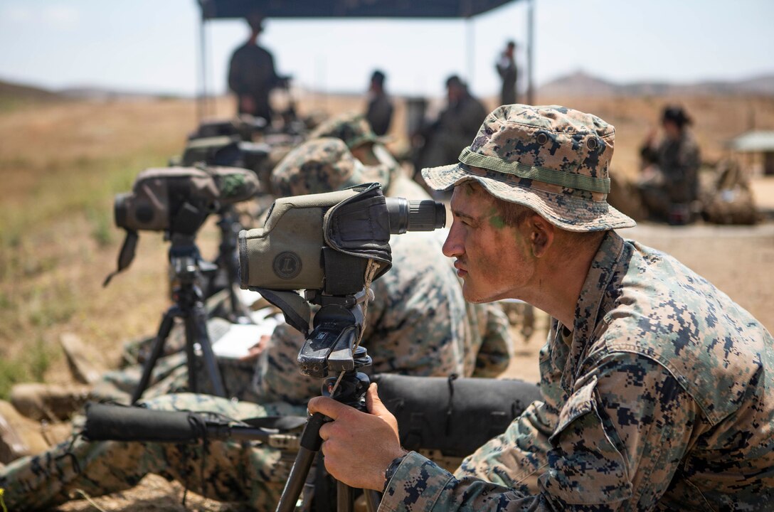 U.S. Marine Lance Cpl. Norman Ballard, a student with the Scout Sniper Course, Reconnaissance Training Company, Advanced Infantry Training Battalion, School of Infantry - West, observes his targets before a live-fire exercise on Range 223B on Marine Corps Base Camp Pendleton, California, July 23, 2020. The students were firing on an unknown distance range, designed to test skills of the Marines and strengthen the communication between the marksman and their observer. (U.S. Marine Corps photo by Lance Cpl. Drake Nickels)