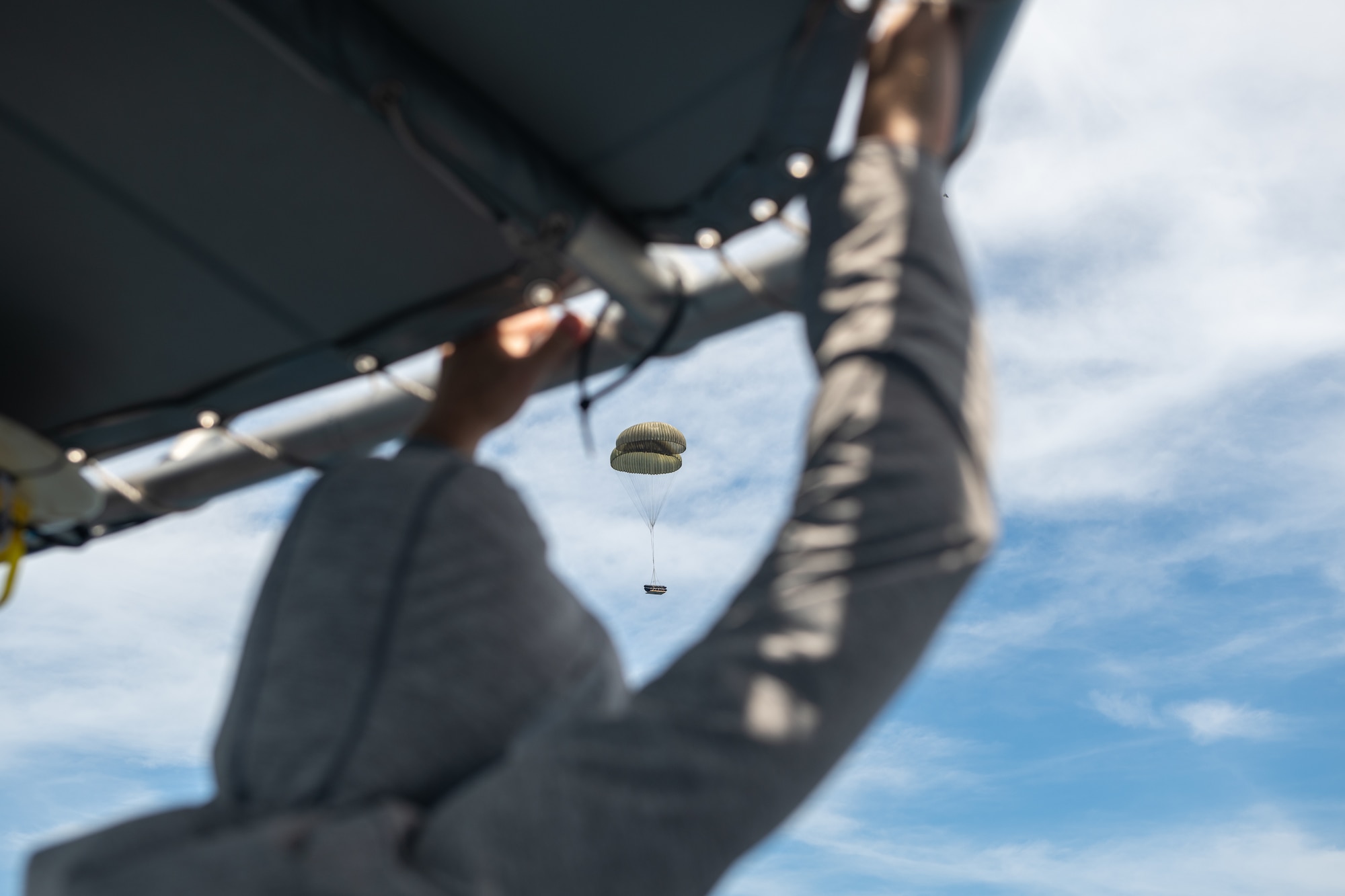 A package attached to parachutes floats into the ocean.