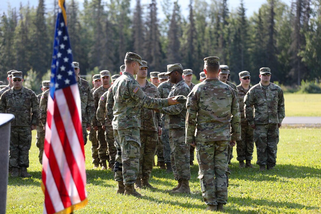 Alaska Army National Guard Capt. Edwin Higginbotham, left, 207th Engineer Utilities Detachment commander, assists Staff Sgt. Jonathan Thomas, training noncommissioned officer, with casing the colors signifying the unit's deactivation at a ceremony at the Camp Carroll flagpole on Joint Base Elmendorf-Richardson, Alaska, Aug. 5, 2023.