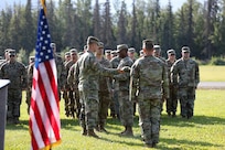 Alaska Army National Guard Capt. Edwin Higginbotham, left, 207th Engineer Utilities Detachment commander, assists Staff Sgt. Jonathan Thomas, training noncommissioned officer, with casing the colors signifying the unit's deactivation at a ceremony at the Camp Carroll flagpole on Joint Base Elmendorf-Richardson, Alaska, Aug. 5, 2023.