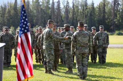 Alaska Army National Guard Capt. Edwin Higginbotham, left, 207th Engineer Utilities Detachment commander, assists Staff Sgt. Jonathan Thomas, training noncommissioned officer, with casing the colors signifying the unit's deactivation at a ceremony at the Camp Carroll flagpole on Joint Base Elmendorf-Richardson, Alaska, Aug. 5, 2023.