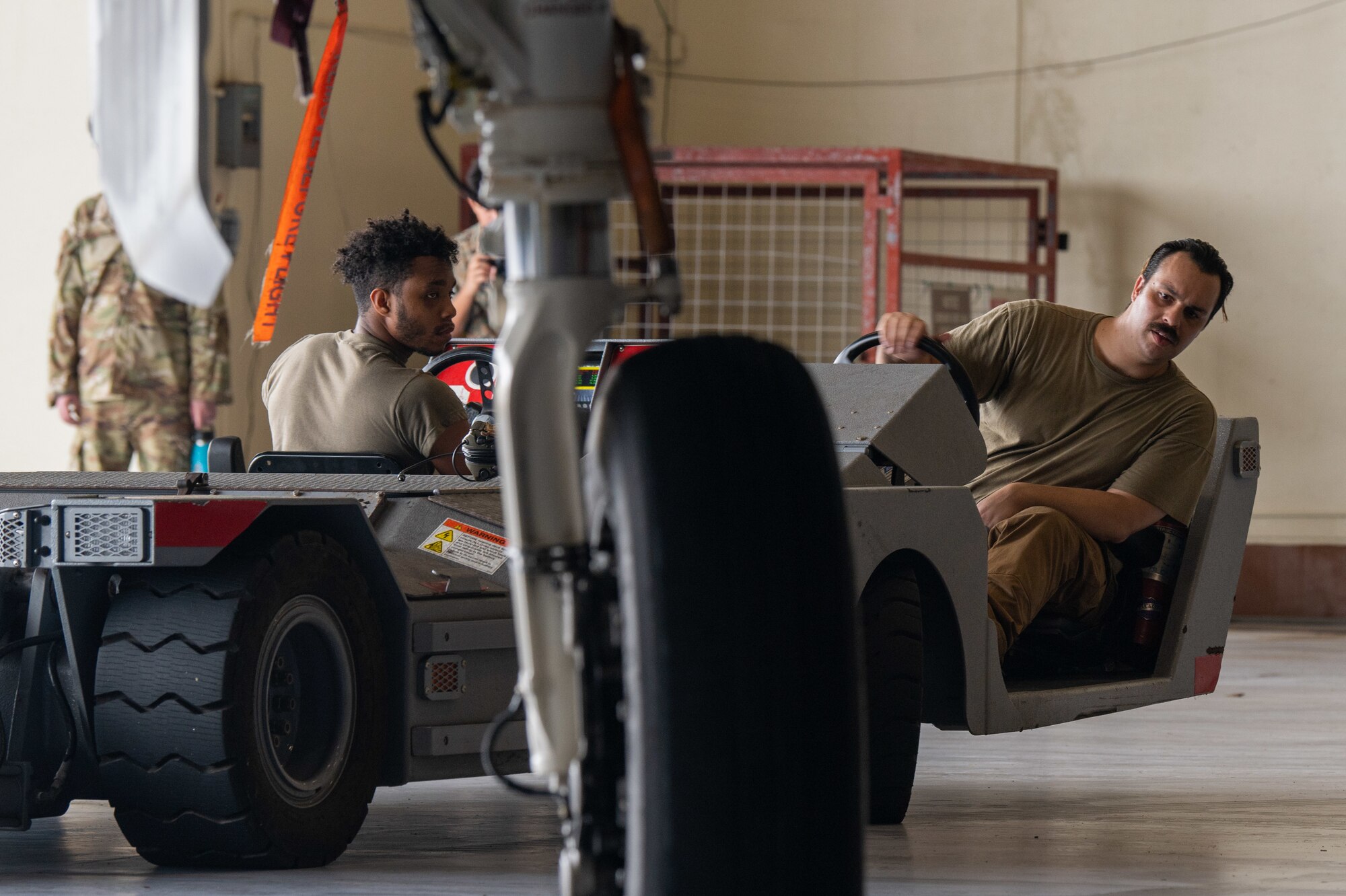 Airmen drive an aircraft towing vehicle.