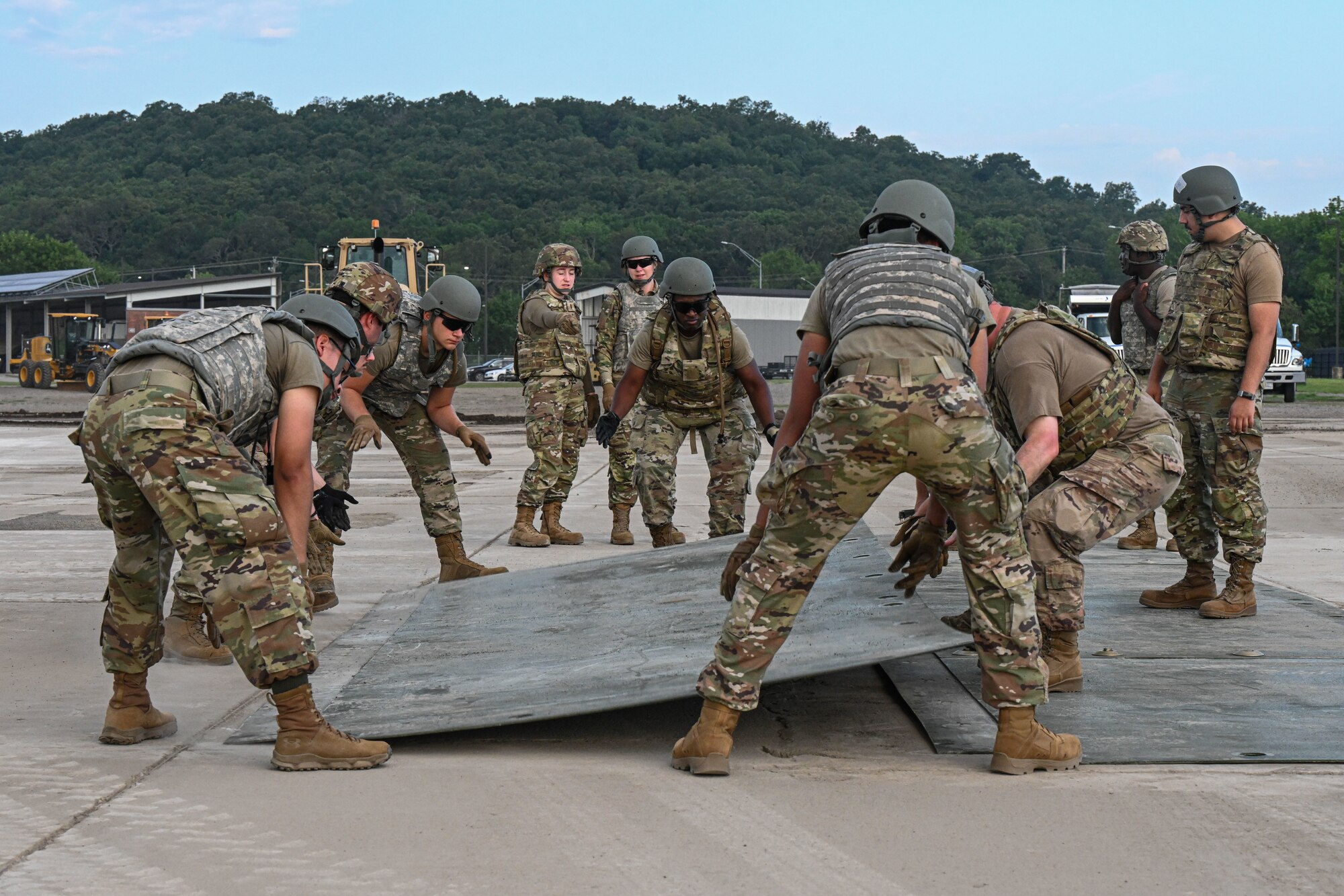 Airmen put down a piece of sheet metal.
