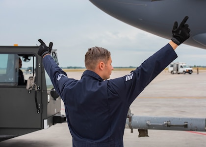 U.S. Air Force Staff Sgt. Randy Davis, 5th Aircraft Maintenance Squadron maintenance apprentice, gives hand signals to his team during the Global Strike Challenge at Minot Air Force Base, North Dakota, Aug. 4, 2023. Davis directed his team during the precision towing portion of the Global Strike Challenge. (U.S. Air Force photo by Airman 1st Class Kyle Wilson)