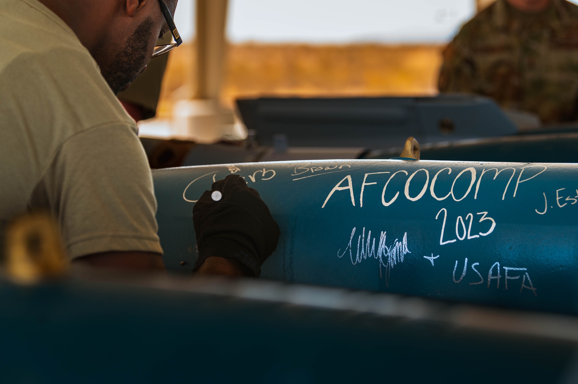 U.S. Air Force Airman 1st Class Vincent Pattio, 56th Equipment Maintenance Squadron equipment specialist, signs a GBU-12 Paveway II bomb.