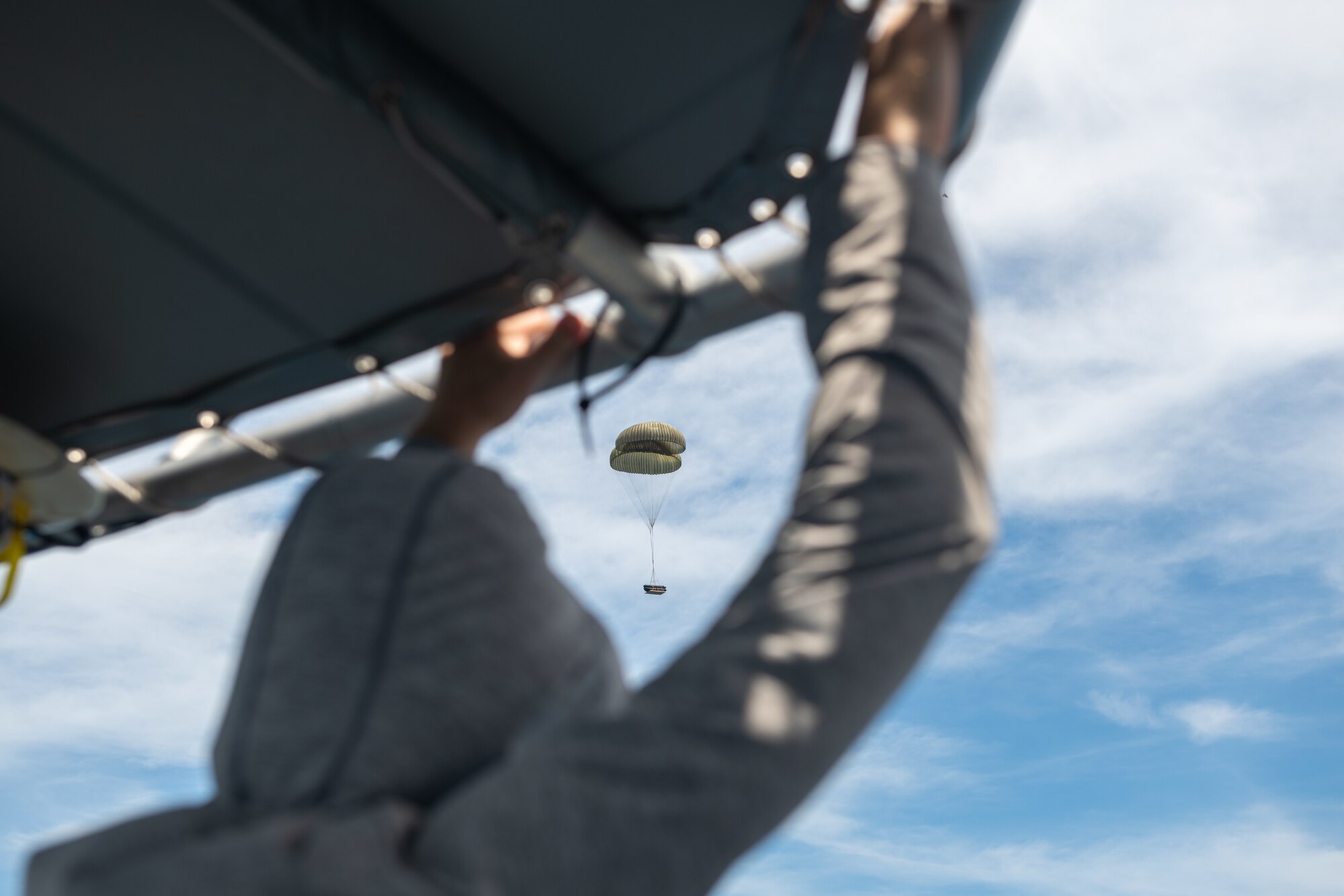 A package attached to parachutes floats into the ocean.
