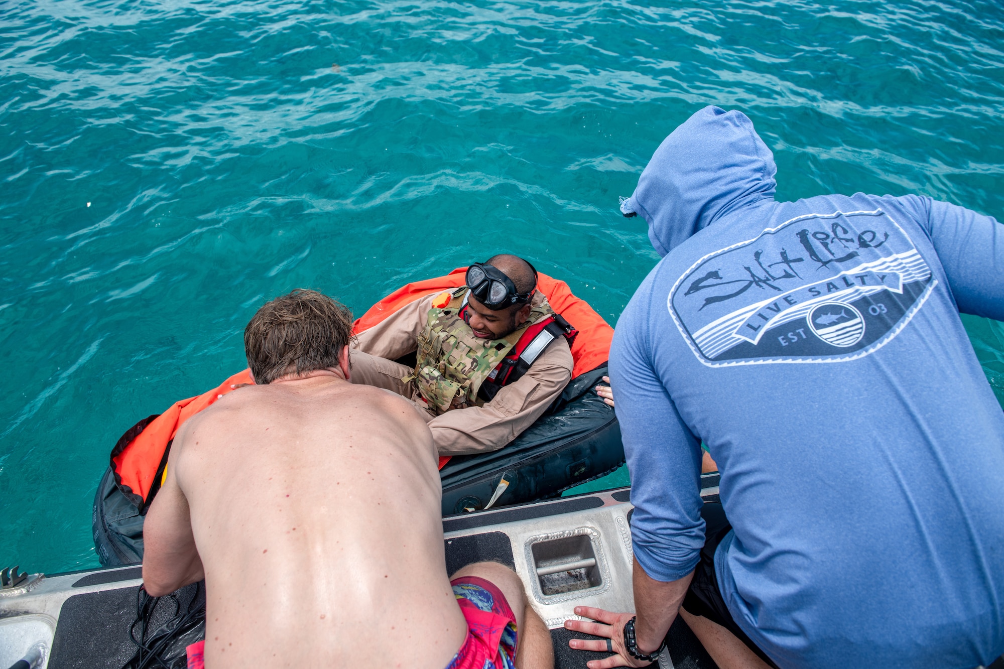 Two men help a man in a raft