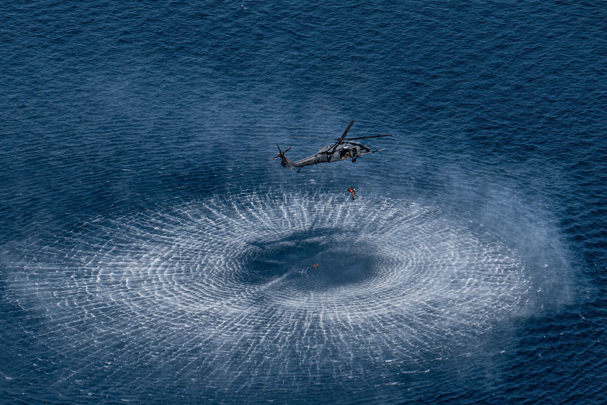 A U.S. Air Force HH-60G Pavehawk assigned to the 33rd Rescue Squadron retrieves pararescuemen and patients from the water during open water rescue training off the shores of Okinawa, Japan, July 20, 2023. Working with HC-130J Super Hercules assigned to the 79th RQS from Davis-Monthan Air Force Base, pararescuemen and rescue craft were deployed to rescue simulated patients and conduct medical treatment until extracted via HH-60G. (U.S. Air Force photo by Senior Airman Cedrique Oldaker)