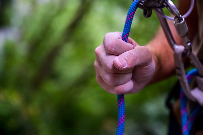 U.S. Air Force Senior Airman Sean Carey, 31st Maintenance group aerospace ground equipment journeyman, holds a rope while being the belayer for his climbing partner at a rock-climbing wall.