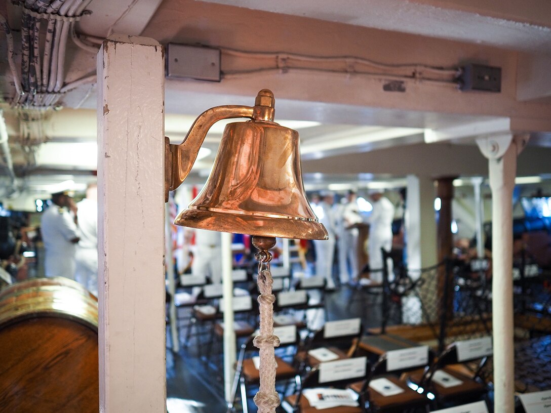 A shiny brass bell is attached to a white pillar onboard a ship