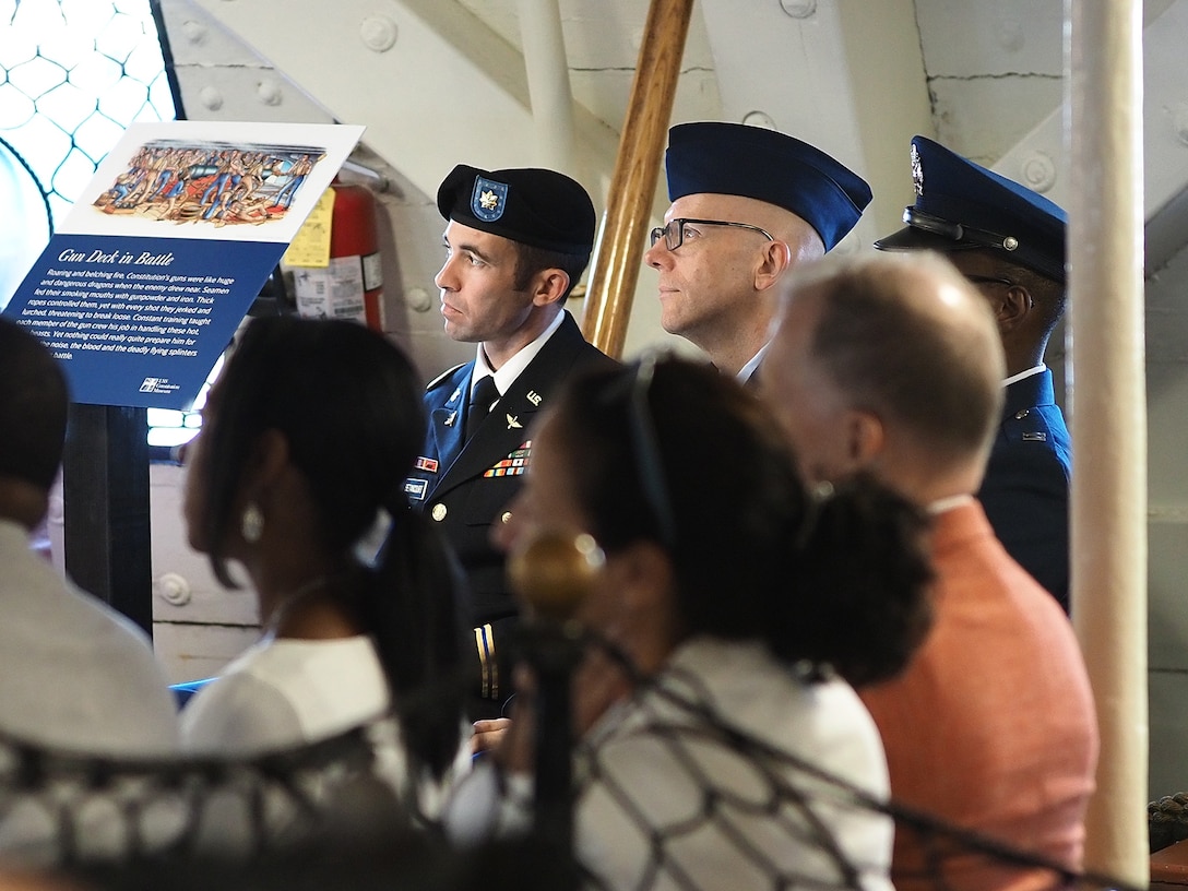 Two men in uniform sit next to a small group of people