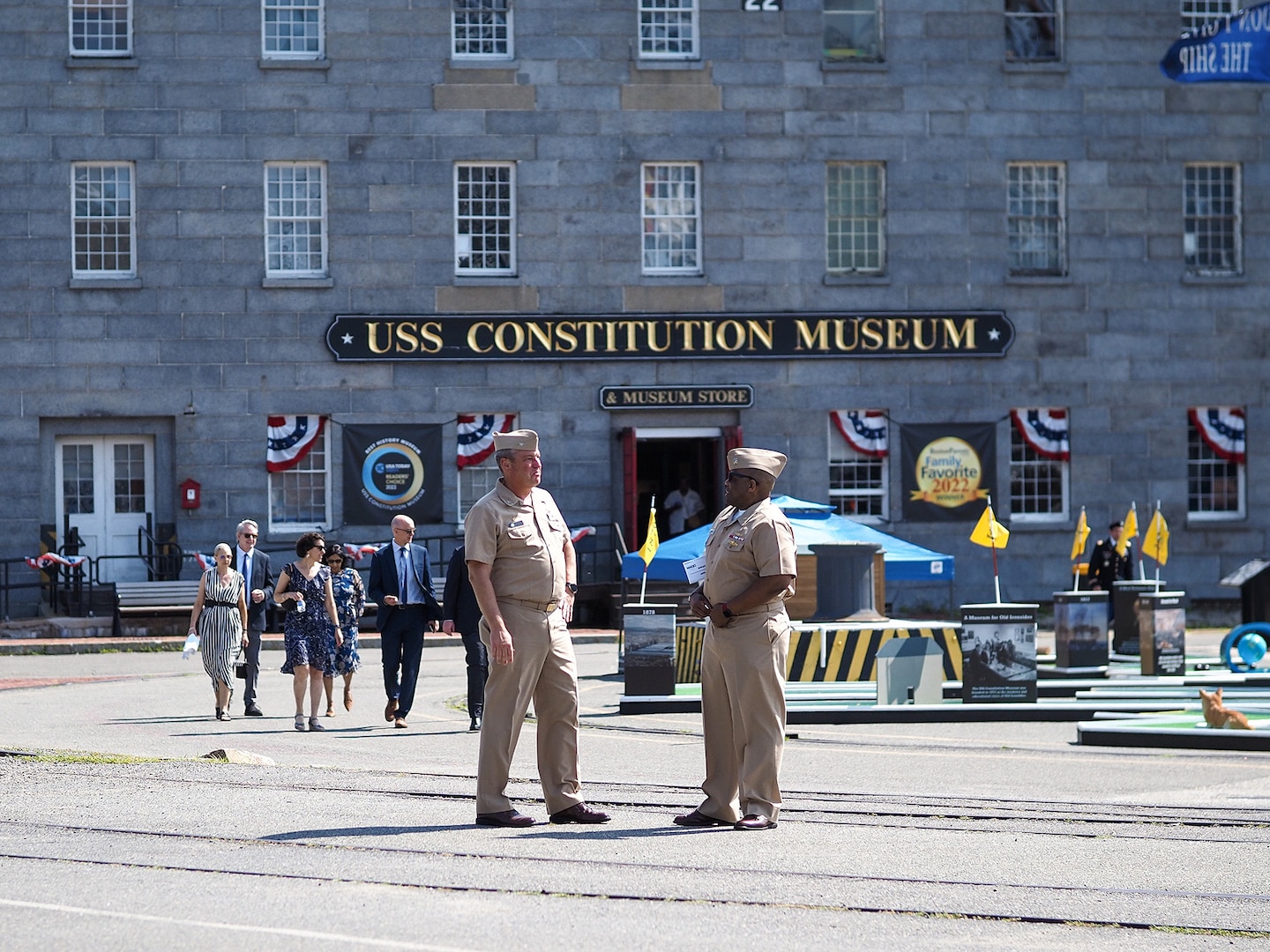 Two Navy officers in khaki uniforms stand outside a museum