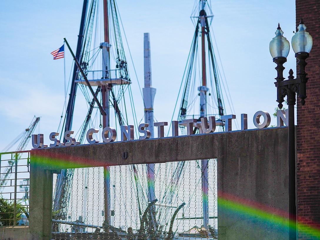 A sign outside the USS Constitution, with the masts of the ship in the background