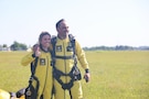 man and women wearing yellow jumpsuits standing in a field.