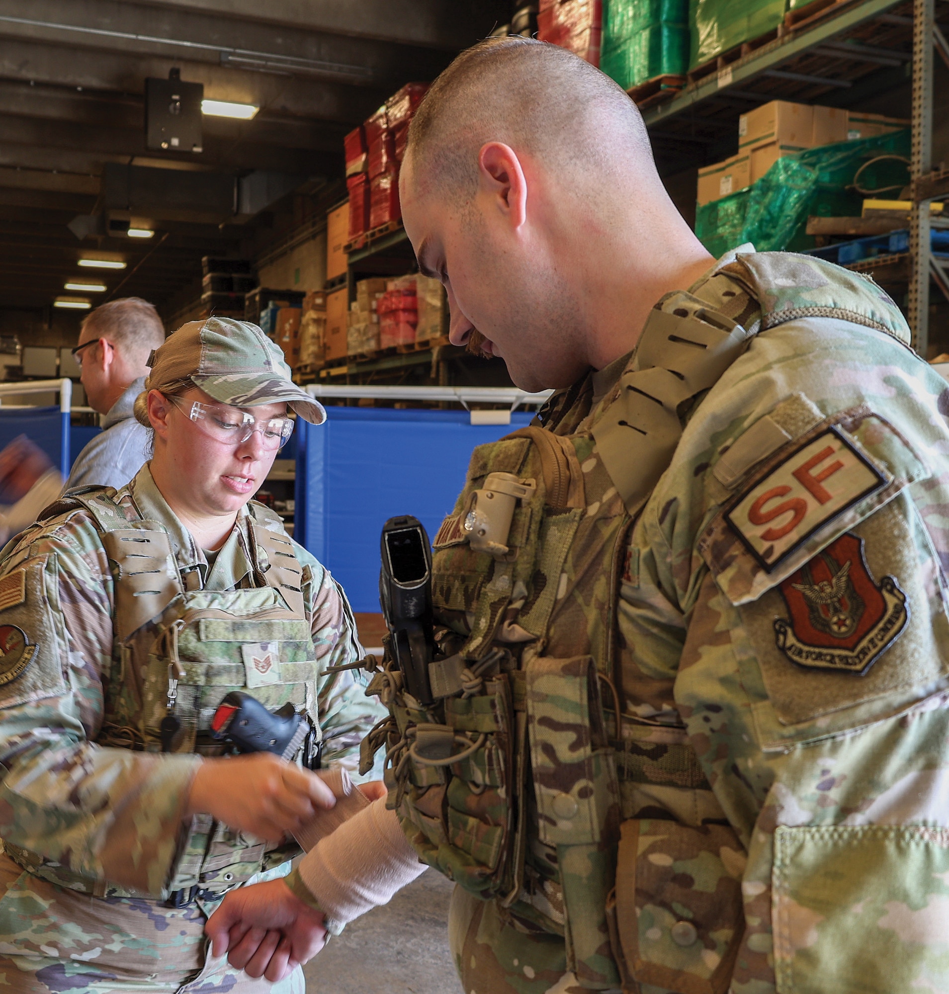U.S. Air Force Staff Sgt. Alexis Williams, left, 445th Security Forces Squadron command support staff, practices wrapping a wound on Master Sgt. Justin Van Niman, right, 445th SFS Training and Readiness noncommissioned officer in charge, during active shooter training at Calamityville, Fairborn, Ohio, July 14, 2023. In addition to learning how to properly respond to active shooter scenarios, participants also learned critical care such as wrapping a wound, applying a tourniquet and more. (U.S. Air Force photo by Amanda Dick)