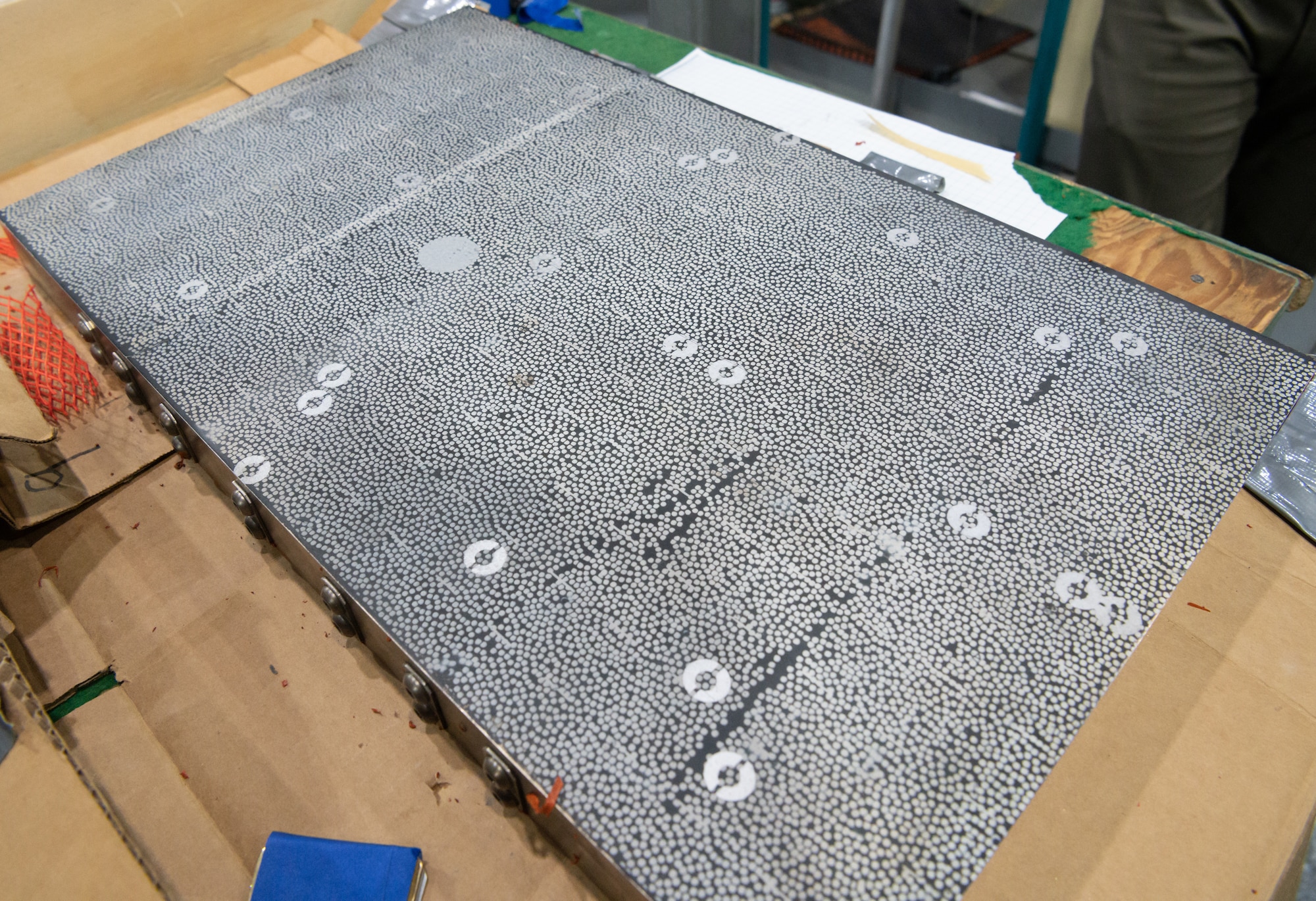 A panel constructed to be representative of an aerospace vehicle fuselage in material type, weight, thickness and support sits on a table in the von Kármán Gas Dynamics Facility at Arnold Air Force Base, Tenn., May 2, 2023. The panel was subjected to hypersonic airflows to observe and measure the effects of the heating which occurs under those conditions. The dot pattern is specifically designed to enable cameras to measure deformation in the panel. Researchers were also able to visibly observe the deformation occurring, including a “snap-through” moment when a section went from concave to convex. (U.S. Air Force photo by Jill Pickett)
