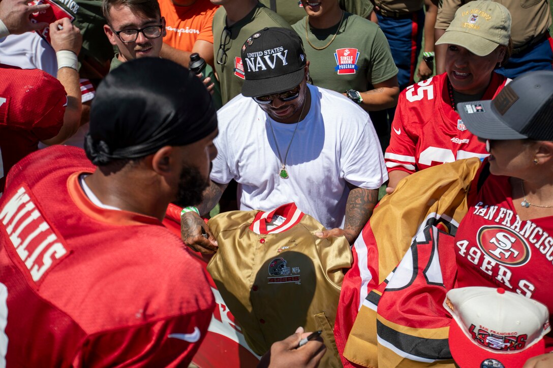 Brayden Willis, left, tight end for the San Francisco 49ers, signs a jacket for Defense Logistics Agency Distribution San Joaquin, California, employees at the 49ers Training Camp on Friday, Aug. 4, 2023. DLA photo by Julian Temblador.