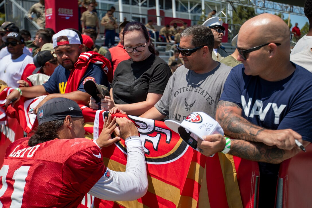 Cameron Latu, tight end for the San Francisco 49ers, signs a flag for Defense Logistics Agency Distribution San Joaquin, California, employees at the 49ers Training Camp on Friday, Aug. 4, 2023. DLA photo by Julian Temblador.