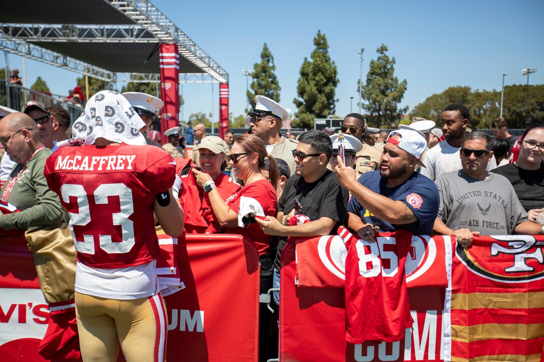 Christian McCaffrey, running back for the San Francisco 49ers, signs a flag for Defense Logistics Agency Distribution San Joaquin, California, employees at the 49ers Training Camp on Friday, Aug. 4, 2023. DLA photo by Julian Temblador.