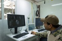A biomedical equipment technician at the U.S. Army Medical Materiel Agency’s Medical Maintenance Operations Division in Tracy, California, performs maintenance on a computed tomography machine. (Photo Credit: Katie Ellis-Warfield)