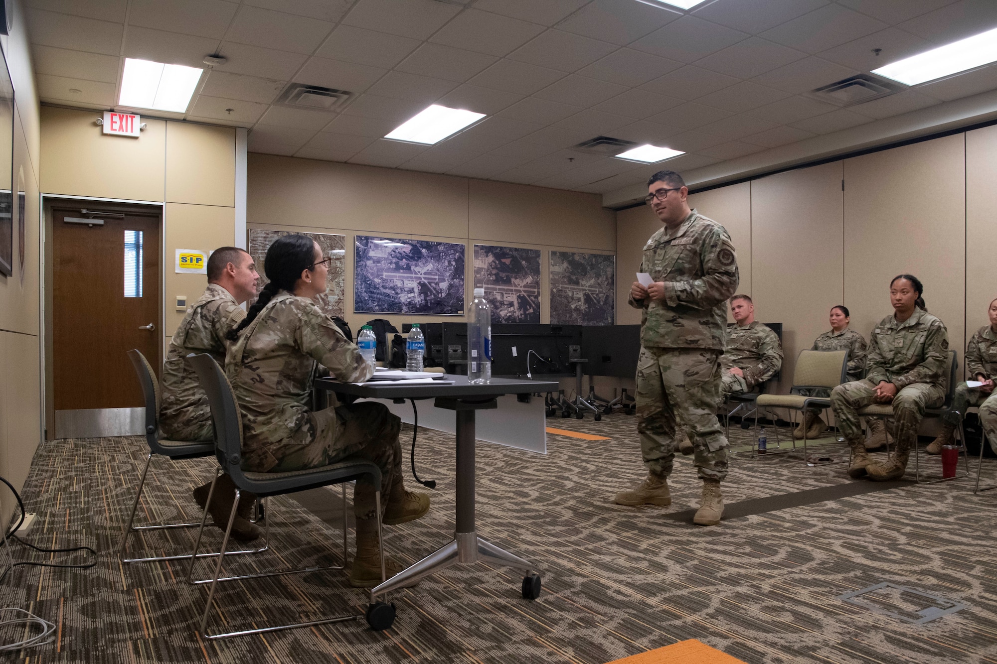 A man speaks to two individuals sitting down.