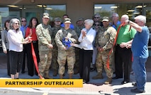 group of men and women cutting a ribbon.