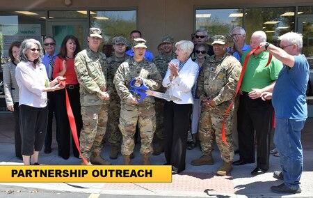 group of men and women cutting a ribbon.