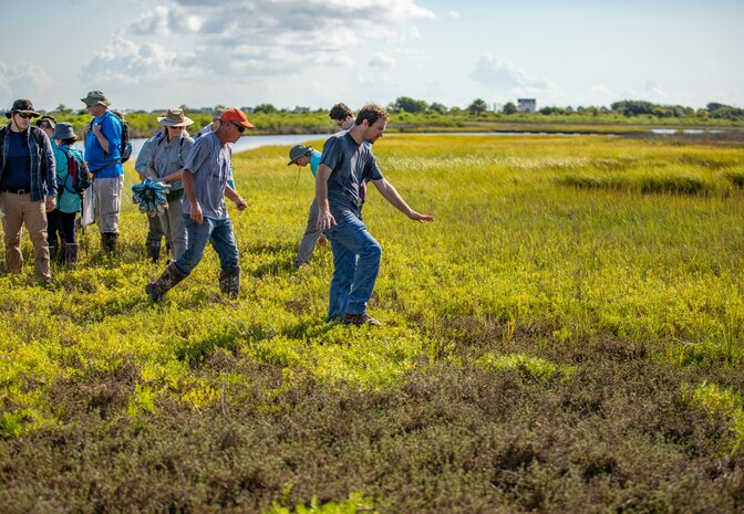 People walk across a field near water