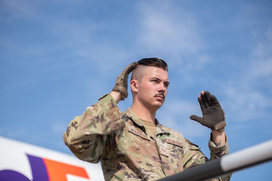Senior Airman Sean Moorhead, 5th Logistics Readiness Squadron air transportation specialist, assists with guiding Bomber Task Force cargo drivers on the flightline at Minot Air Force Base, North Dakota, Aug. 3, 2023. BTF missions enhance the readiness and training necessary to respond to any potential crisis or challenge across the globe. (U.S. Air Force photo by Trust Tate)