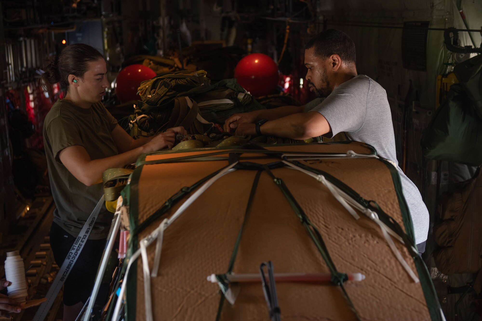 U.S. Air Force aircrew flight equipment Airmen assigned to the 31st Rescue Squadron secure cargo inside a HC-130J Super Hercules before taking off at Kadena Air Base, Japan, July 20, 2023. The 31st RQS conducted water rescue training with the 33rd RQS and the 79th RQS from Davis-Monthan Air Force Base, allowing units to work alongside all aspects of rescue operations. (U.S. Air Force photo by Senior Airman Cedrique Oldaker)
