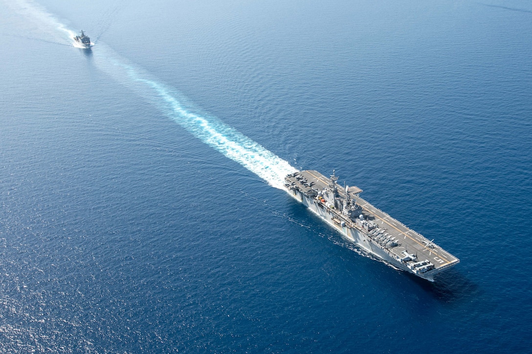 Two Navy ships sail in open water.