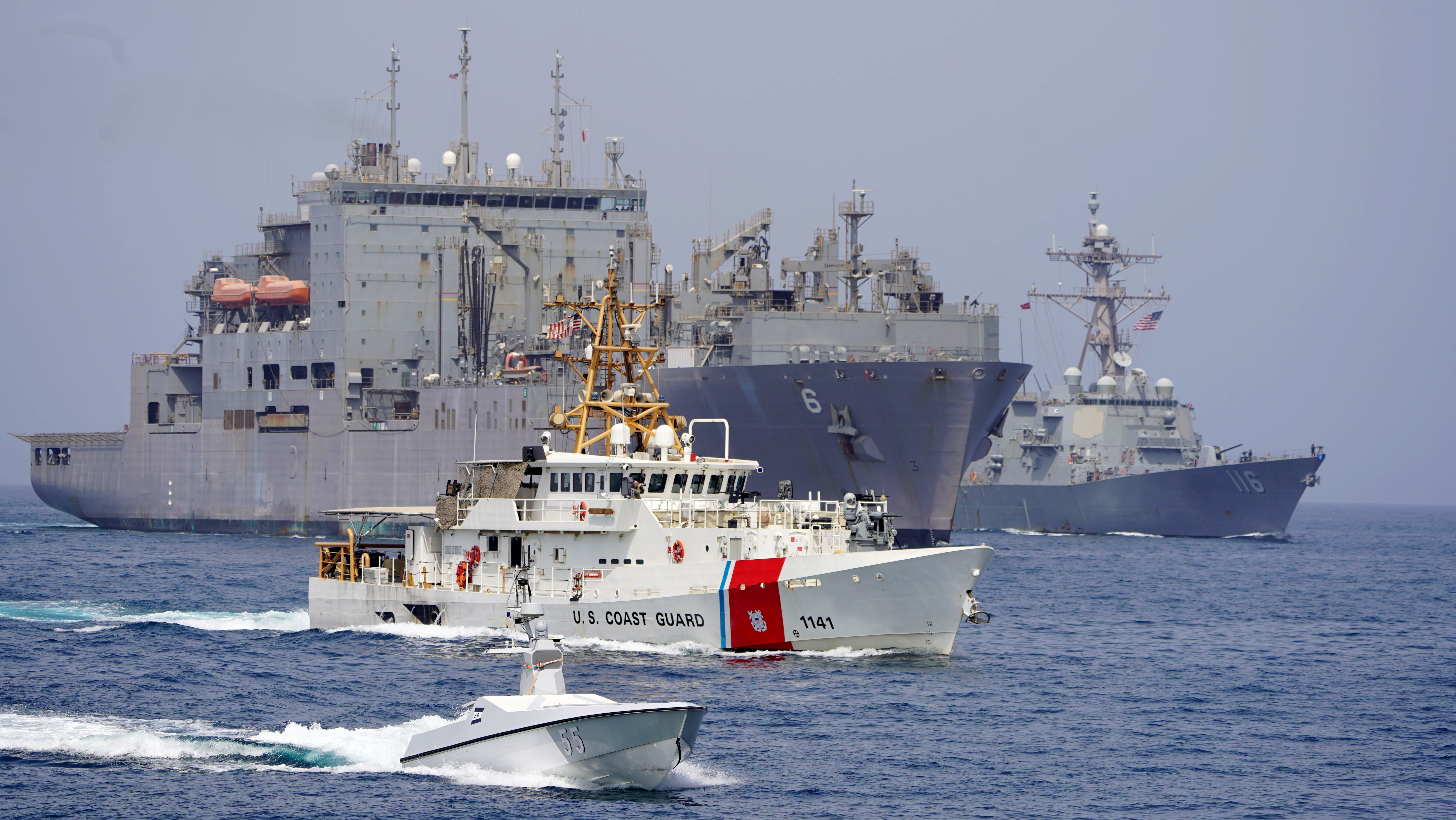 An unmanned surface vessel, front, SCGC Charles Moulthrope (WPC 1141), USNS Amelia Earhart (T-AKE 6) and USS Thomas Hudner (DDG 116) transit the Strait of Hormuz.