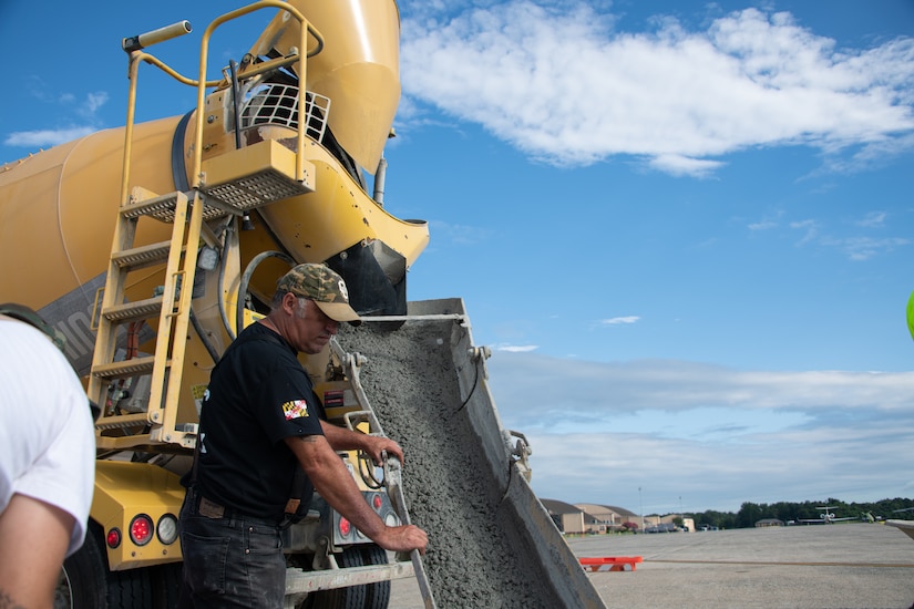 Donald Roscom, 316th Civil Engineer Squadron construction equipment operator, monitors wet cement pouring from a concrete mixer into a readied hole in the flightline at Joint Base Andrews, Maryland, Aug. 8, 2023.