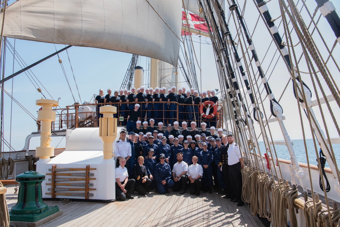USCGC Eagle (WIX 327) crewmembers met with the Danish training ship Danmark, the crews stood together for a photo on the waist of the Danmark, June 14, 2023, while under sail in the Baltic Sea. Eagle is a tall ship used as a training platform for future Coast Guard Academy officers as well as a vessel utilized for establishing and maintaining domestic and international relationships. (U.S. Coast Guard photo by Petty Officer 3rd Class Carmen Caver)