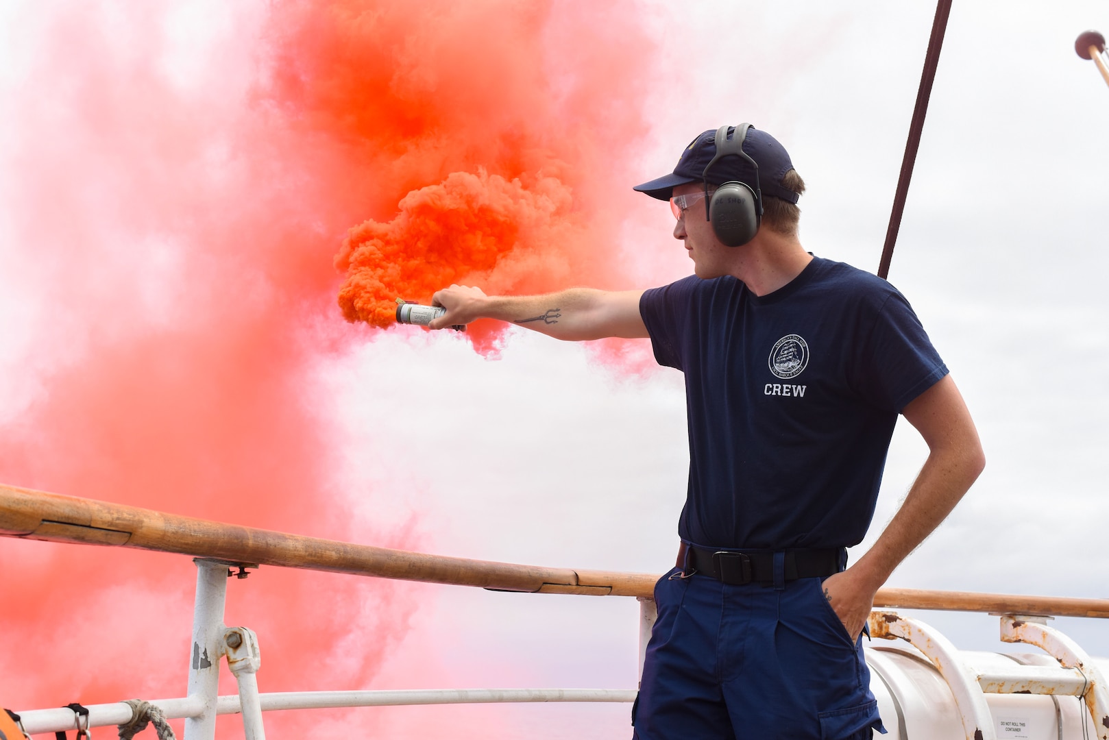 U.S. Coast Guard Petty Officer 3rd Class Benjamin Thomas, a boatswain’s mate aboard USCGC Eagle (WIX 327), test releases a smoke flare on the stern of USCGC Eagle (WIX 327), July 5, 2023, while underway in the Atlantic Ocean. Eagle is a tall ship used as a training platform for future Coast Guard officers. (U.S. Coast Guard photo by Petty Officer 3rd Class Carmen Caver)