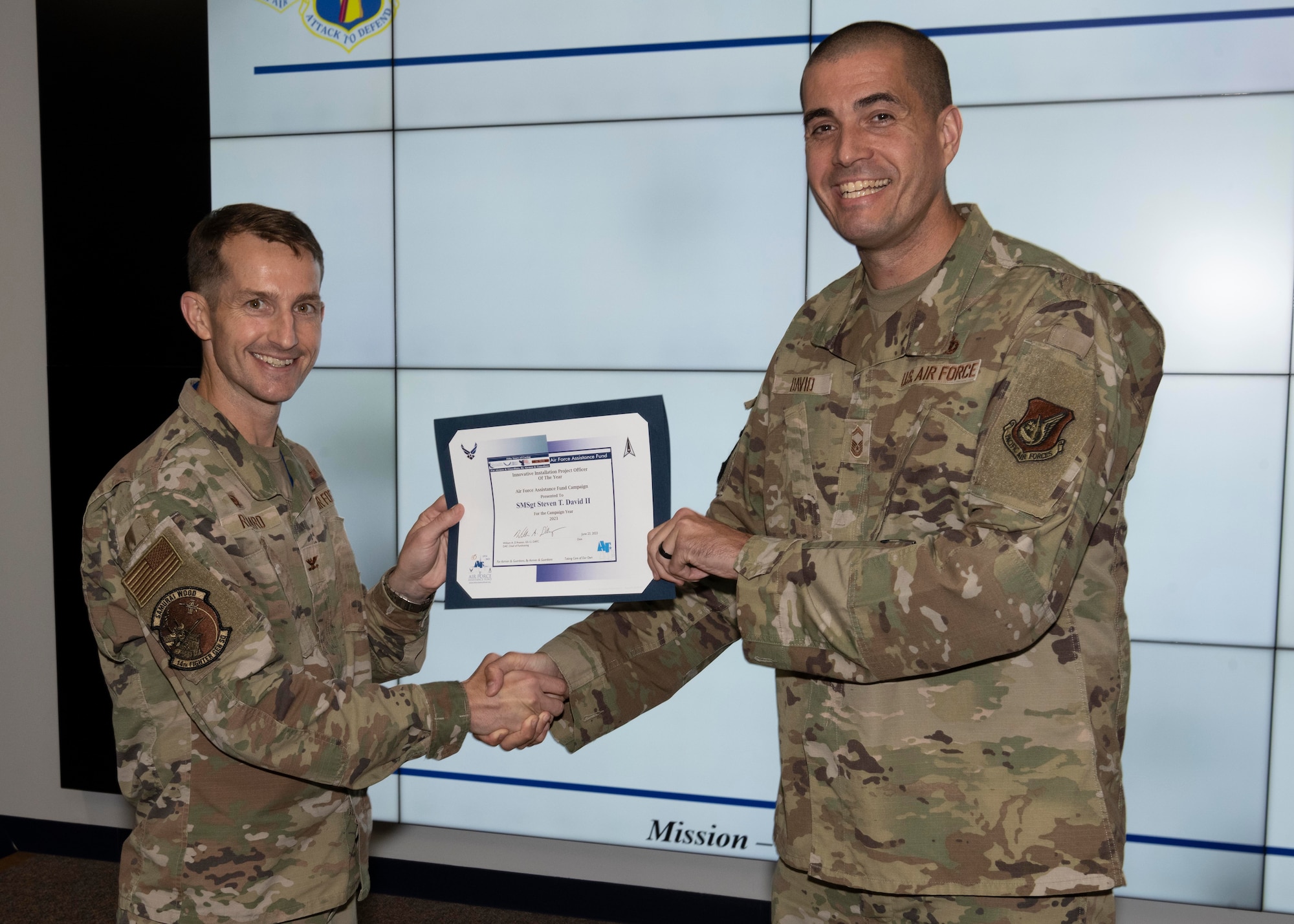 Two military members hold an award.