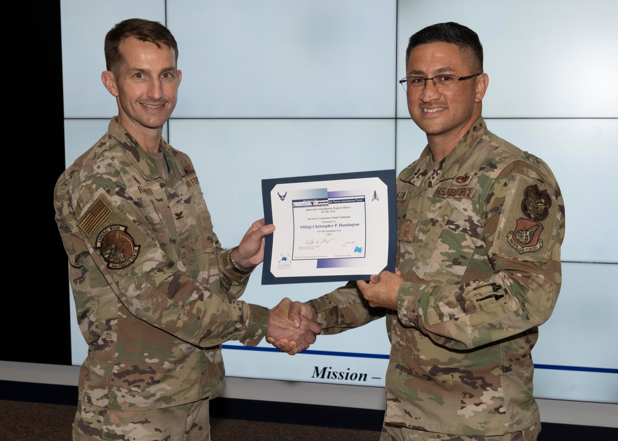Two military members hold an award.