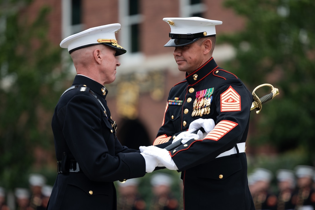 The Assistant Commandant of the Marine Corps Gen. Eric M. Smith passes the noncommissioned officer sword to the incoming Sergeant Major of the Marine Corps Sgt. Maj. Carlos A. Ruiz during the Sergeant Major of the Marine Corps relief and appointment ceremony at Marine Barracks Washington, August 10, 2023.