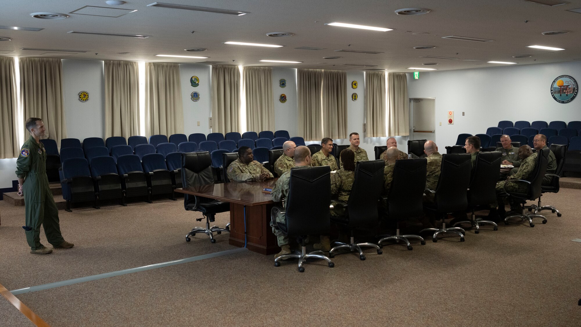 Military members sitting at a table as a brief is given.