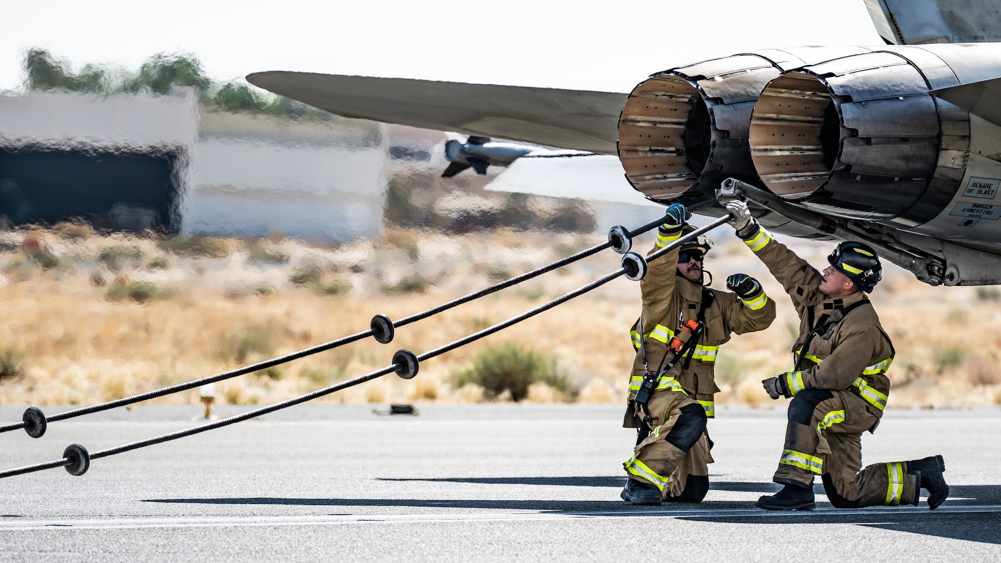 U.S. Air Force fire protection Airmen assigned to the 386th Expeditionary Civil Engineer Squadron disconnect a Kuwait Air Force F/A-18 Super Hornet from a Mobile Aircraft Arresting System (MAAS) at Ali Al Salem Air Base, Kuwait, July 10, 2023. This certification event was beneficial to the U.S. and Kuwait as both parties received more experience using the MAAS, which has been certified to continue providing enhanced stopping power to inbound aircraft for a variety of scenarios. (U.S. Air Force photo by Staff Sgt. Kevin Long)