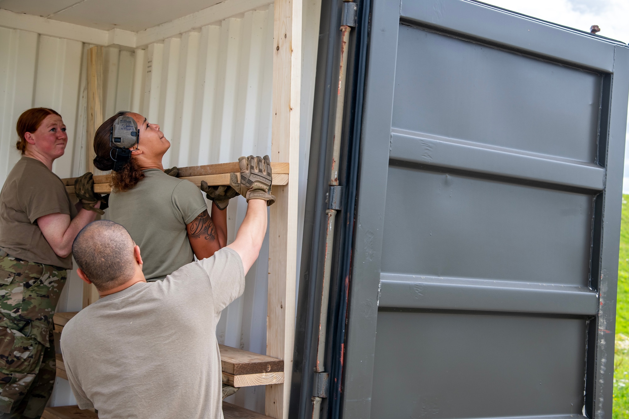 Airmen from the 420th Munitions Squadron place a wooden door side fill into an International Standards Organization container at RAF Welford, England, Aug. 7, 2023. The 420th MUNS conducted operations in support of a week-long Combat Ammunition Production Exercise, which helped strengthen their combat planning and production concepts. (U.S. Air Force photo by Staff Sgt. Eugene Oliver)