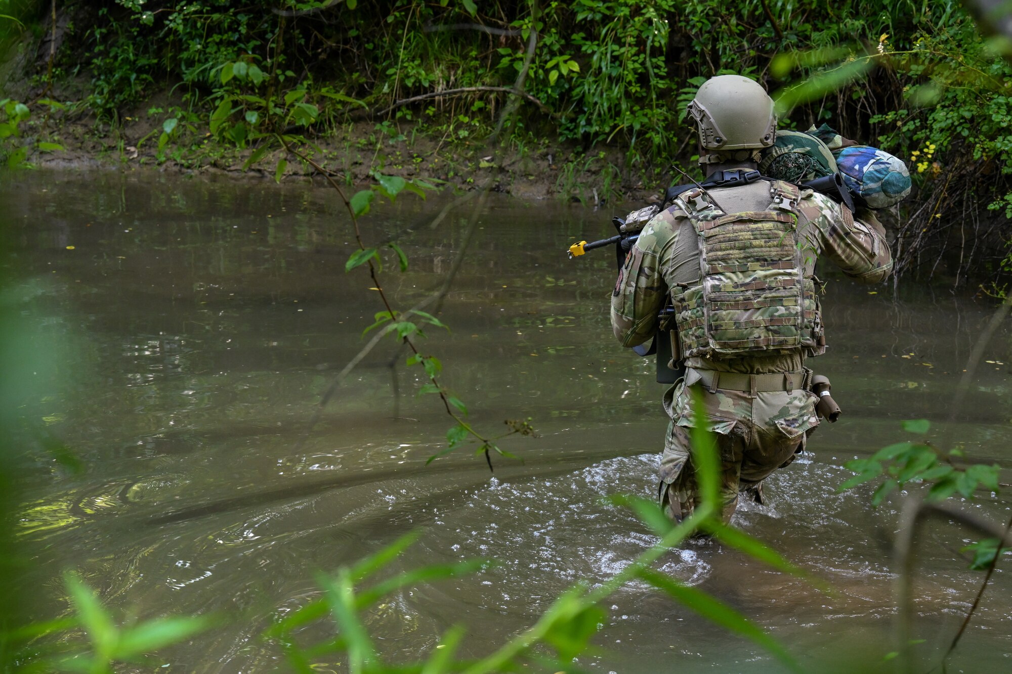 Airman 1st Class Terrance Mack, a Defender assigned to the North Carolina Air National Guard's 145th Security Forces Squadron, walks through a stream during an Integrated Defense Leadership Course training exercise on July 27, 2023, at Camp James A. Garfield Joint Military Training Center, Ohio.