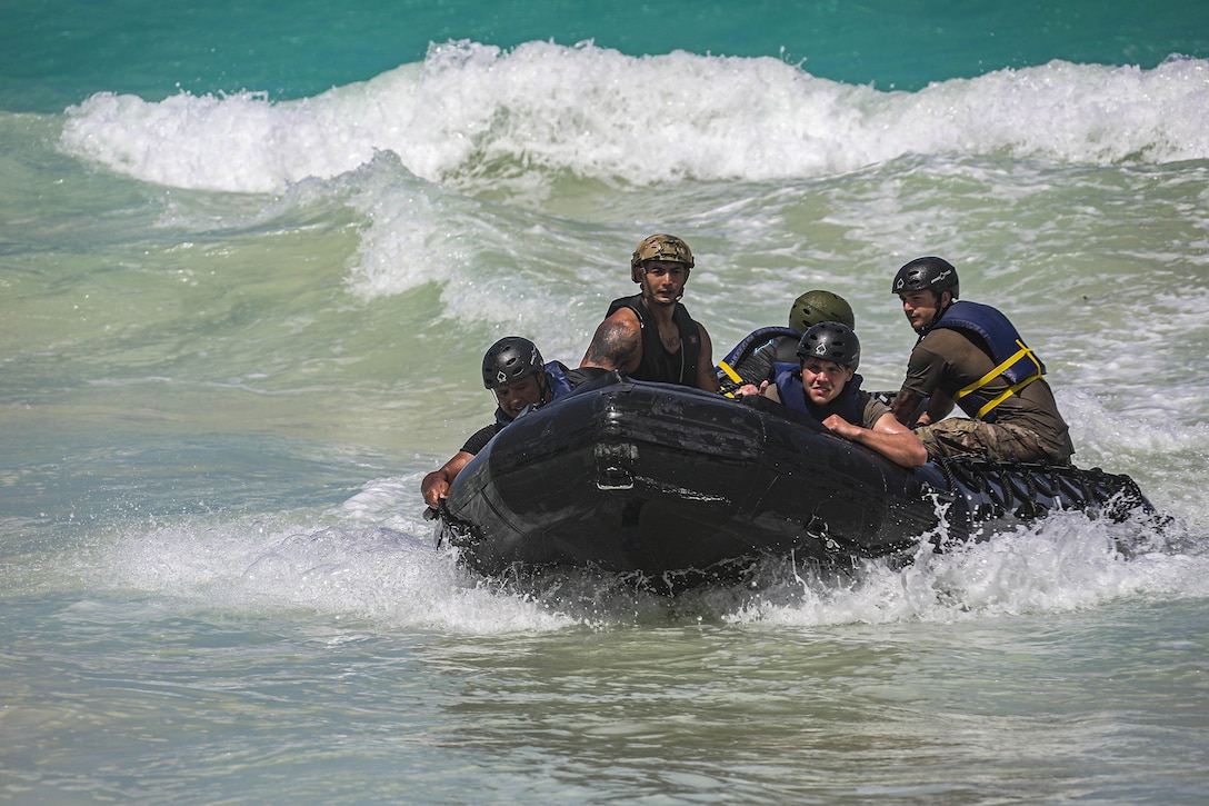 Soldiers ride in a raft as waves lap behind them.
