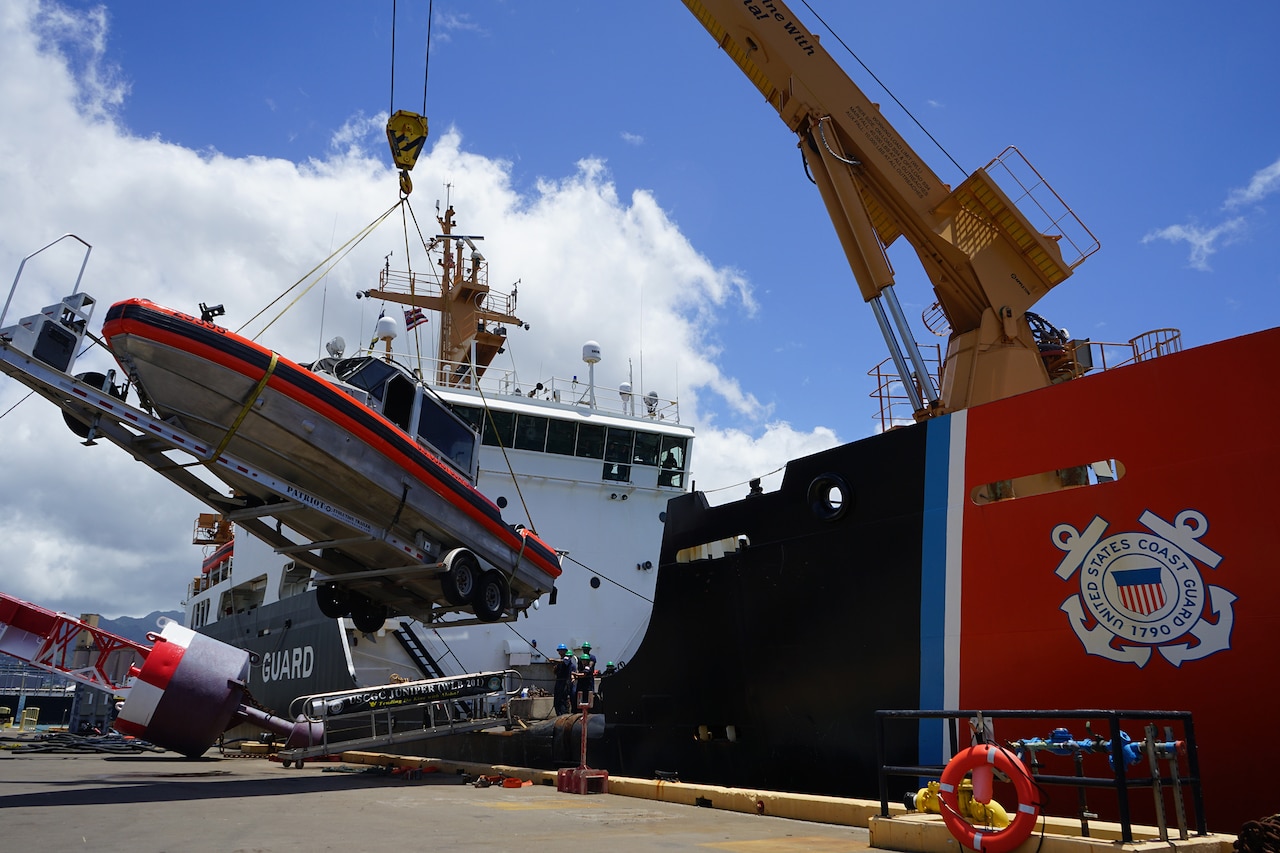 A small boat is lifted onto a Coast Guard vessel.