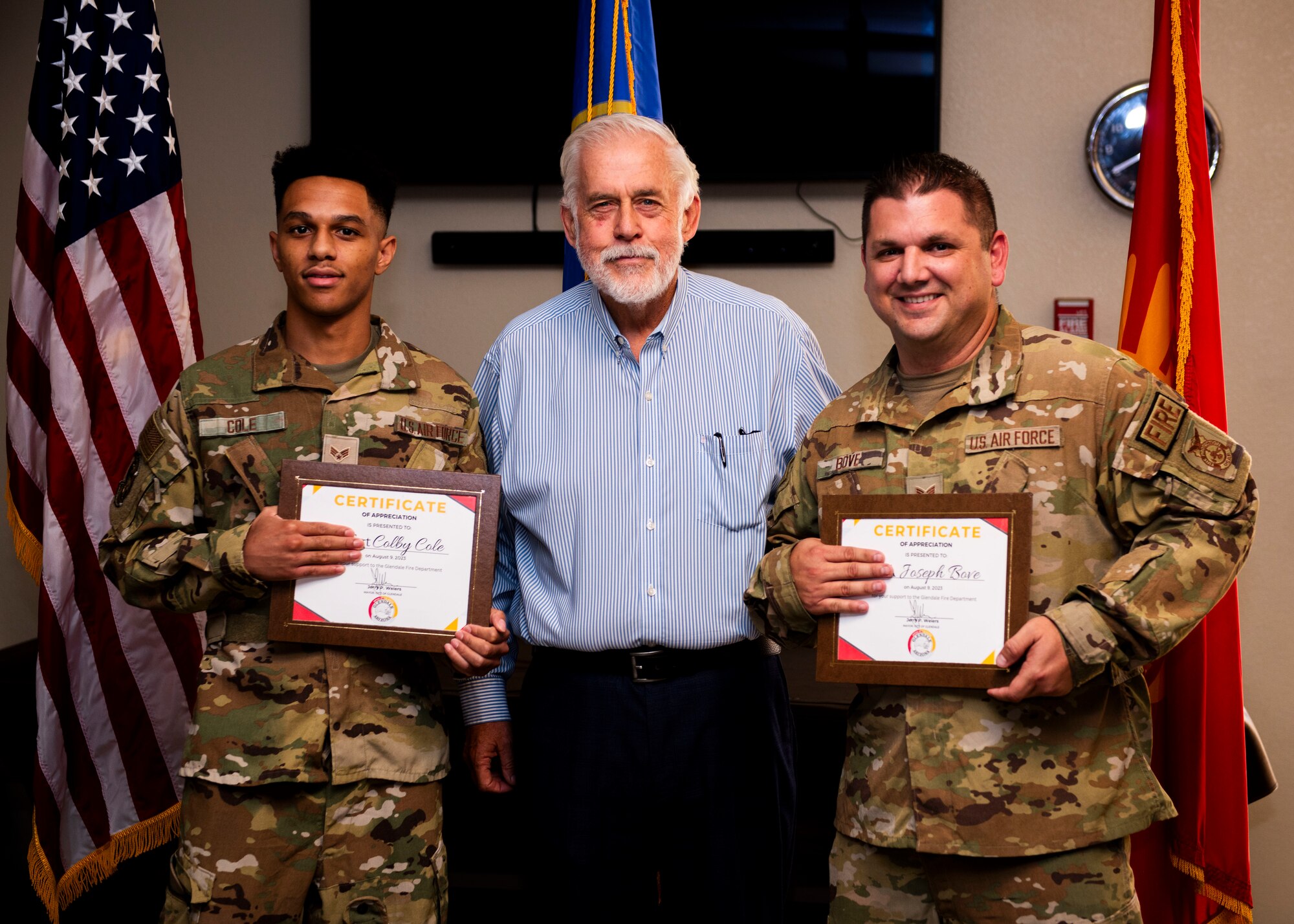 Jerry P. Weiers, Glendale, Arizona mayor, congratulates and coins Staff Sgt. Joseph Bove, 56th Civil Engineer Squadron firefighter, and Senior Airman Colby Cole, 56th CES firefighter, on Glendale, Arizona Aug. 9, 2023, at Luke Air Force Base, Arizona.