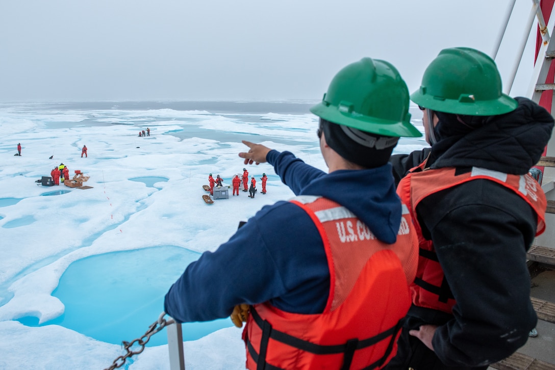 Two U.S. Coast Guard Cutter Healy (WAGB 20) deck department personnel observe science equipment installation on a multi-year ice floe in the Beaufort Sea, Aug. 6, 2023. Healy is the Coast Guard’s only icebreaker specifically designed for Arctic research, as well as the nation’s sole surface presence routinely operating in the Arctic Ocean. (Coast Guard photo by Petty Officer 3rd Class Briana Carter)