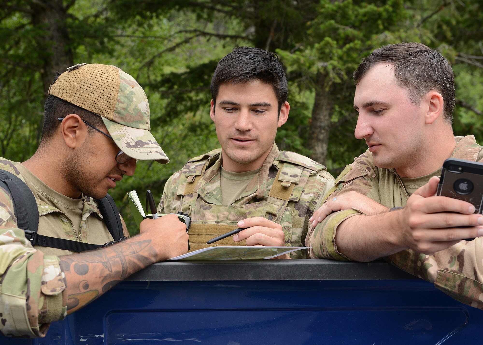 Three men assess a paper map in front of them.
